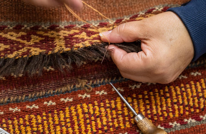 A rug with fringe grooming and repair.