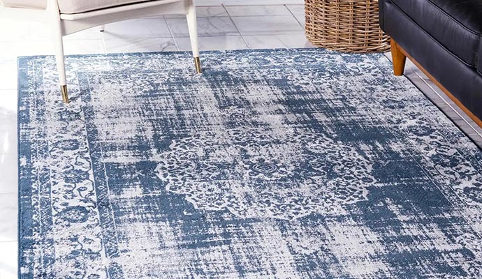 A blue and white distressed patterned area rug on a tiled floor
