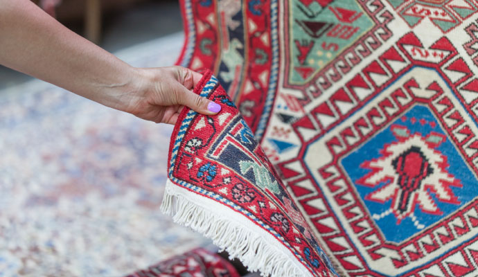 An expert inspecting a fiber-protected rug to evaluate its condition