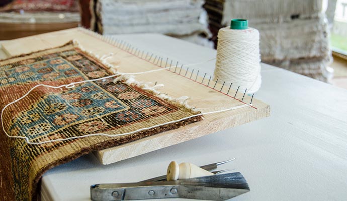 Rug fringe repair and restoration setup on a wooden loom board
