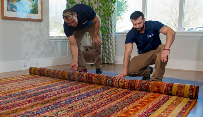 Dalworth Rug Cleaning team unrolling a clean rug