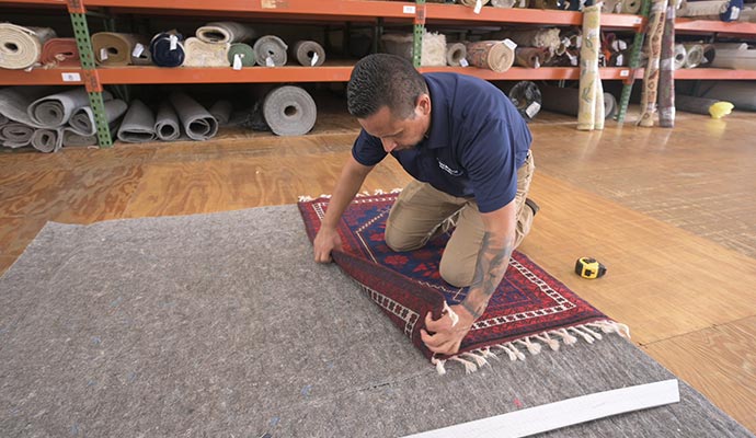 Expert installing custom rug pads under a rug