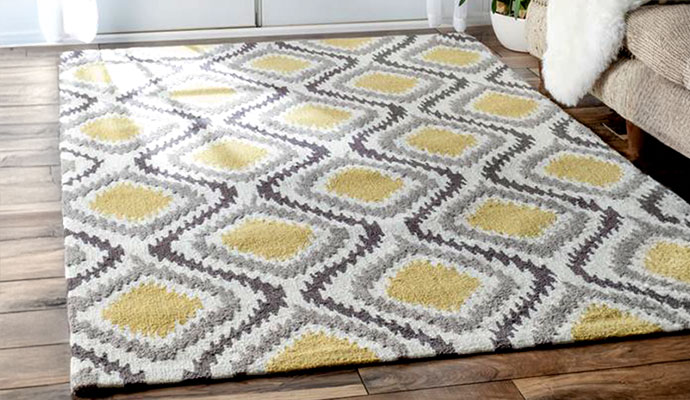 A clean yellow and grey geometric patterned area rug on a hardwood floor with protection treatment