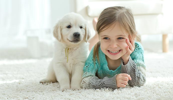 Smiling girl lying on carpet with a cute puppy