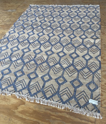 A contemporary flat-woven area rug with a blue geometric diamond pattern on a tan background, fully deep-cleaned, with neatly aligned and detangled white fringes.