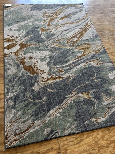 Full view of a residential rug with an abstract design in shades of blue, gray, and gold, showcasing its cleaned and restored condition with improved nap and repaired fibers on a wooden floor.