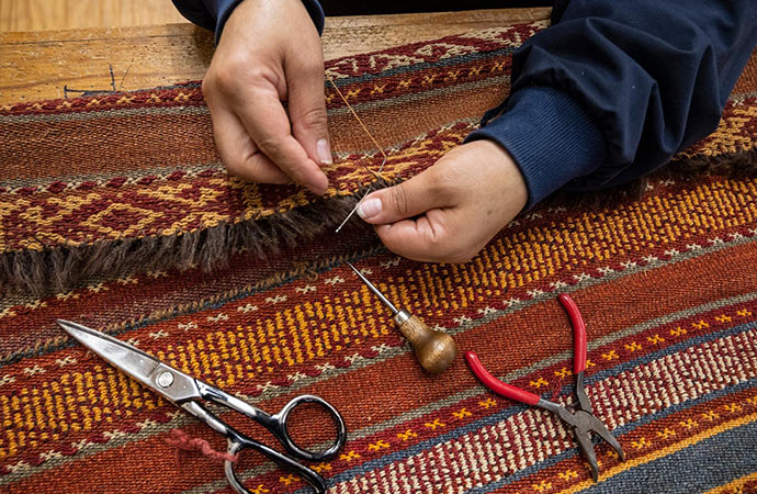 A professional worker repairing rug fringe