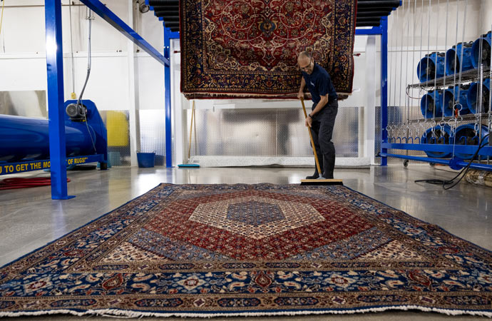 Skilled professionals cleaning a beautiful Iranian rug.