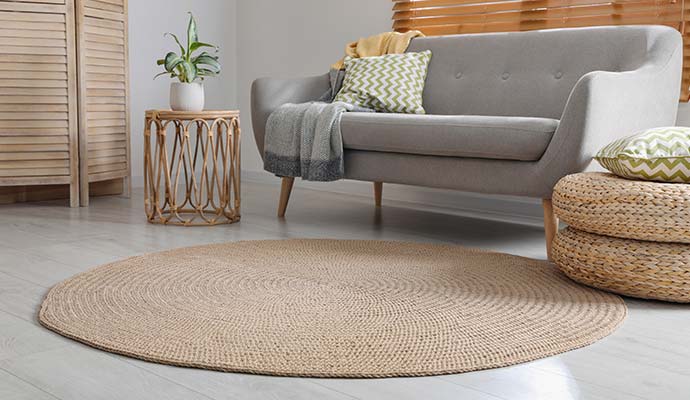 Round braided jute rug on the floor in front of a sofa