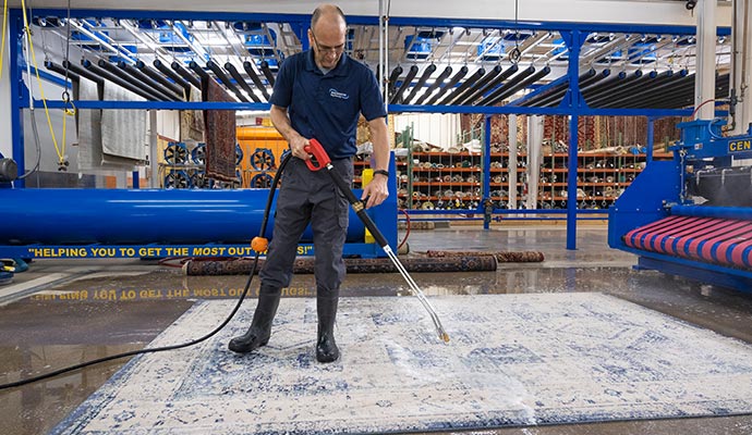 worker cleaning rug with equipments