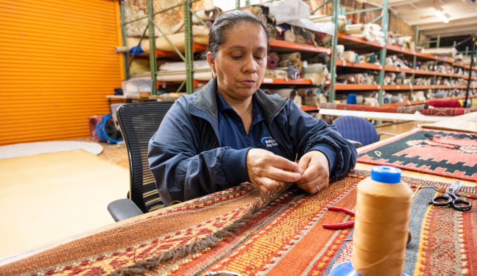 An expert repairing a damaged rug using professional equipment