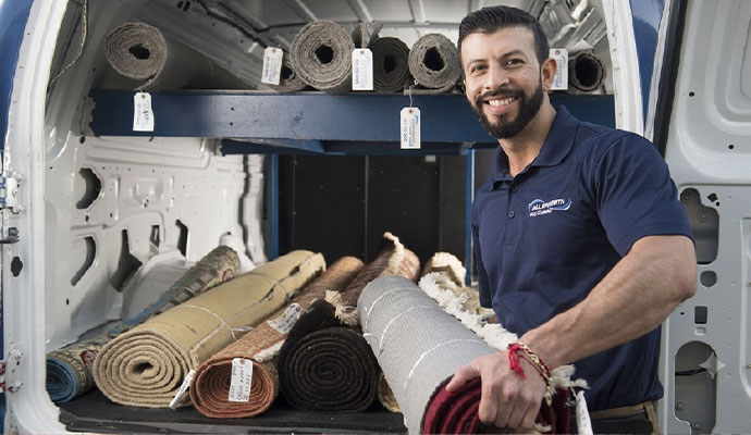 An expert with a rolled rug for delivery