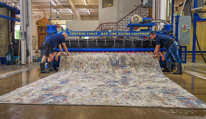 Two experts cleaning a rug with industrial machinery