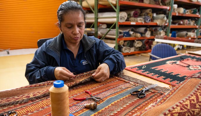 Person repairing rug with sewing equipment
