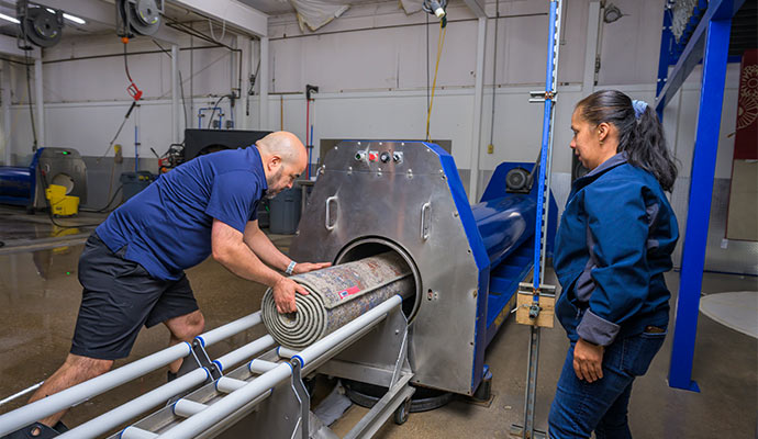 Technicians loading a rug into a drying machine