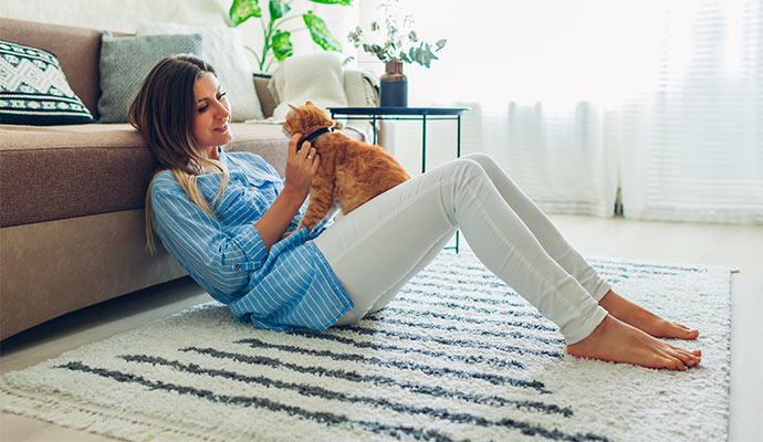 Woman playing with cat on clean iranian rug in living room