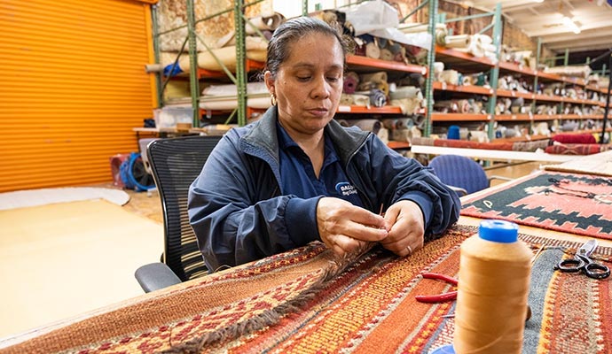 Woman sewing rug fringe in workshop