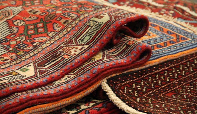 Stack of folded traditional Oriental rugs showing intricate patterns