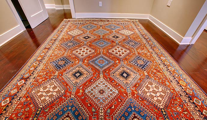 A detailed view of a vibrant, multi-colored patterned indoor rug on a dark wood floor, showcasing preserved color and texture