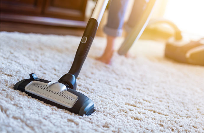 Household rug cleaning with a vacuum cleaner in use.